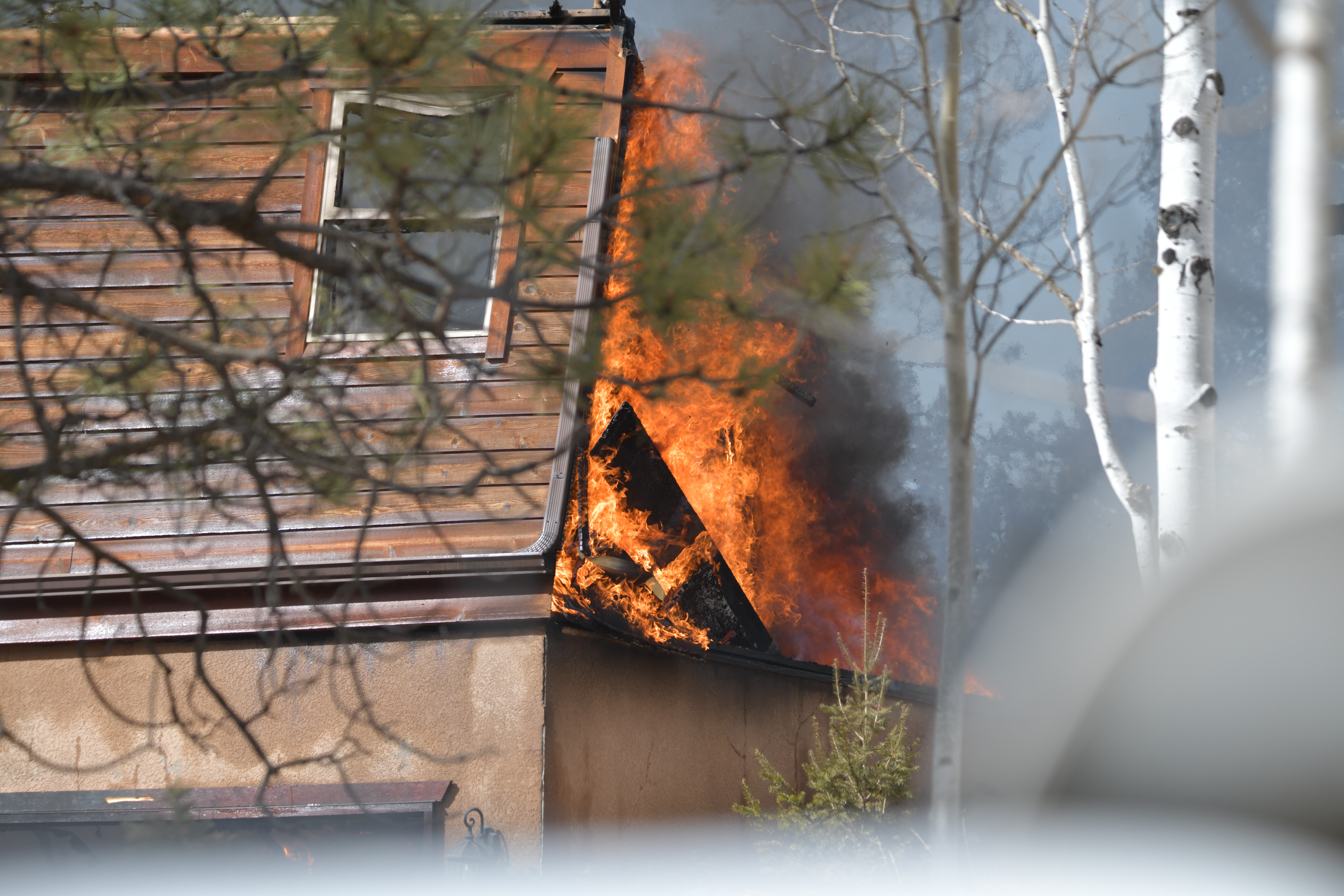 Flames  billowing out of attic of house