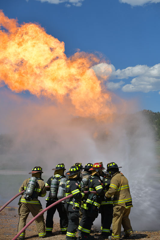 Firefighters with hoses putting water on a 30 foot flame